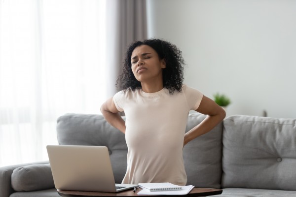 Woman with back pain stretching at her computer.